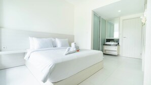 Een moderne hotelkamer met een groot bed, een badkamer met wastafel en een deur naar een andere kamer.