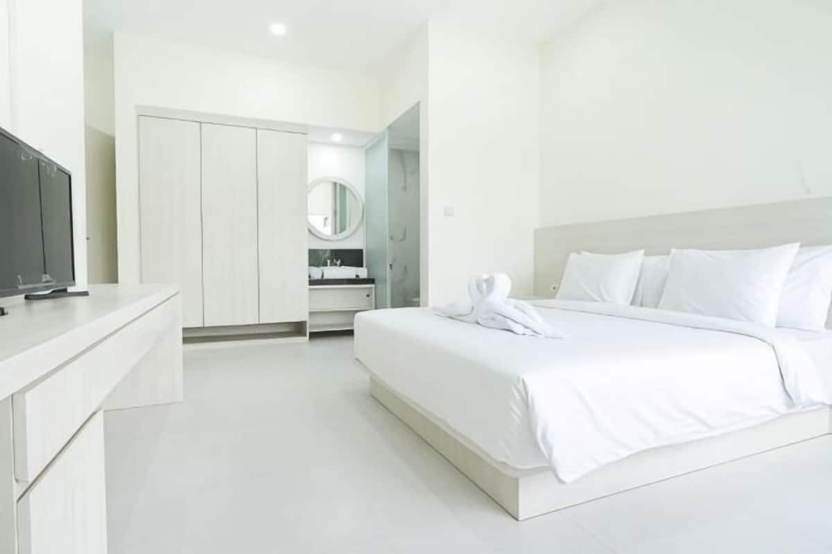 Habitación de hotel con cama, televisión, armario y espejo.