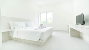 Een moderne, minimalistisch ingerichte slaapkamer met een groot bed, een televisie en een raam met uitzicht op groen.