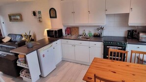 Eine kleine Küche mit weißen Schränken, einem Holztisch und einem eingebauten Backofen.