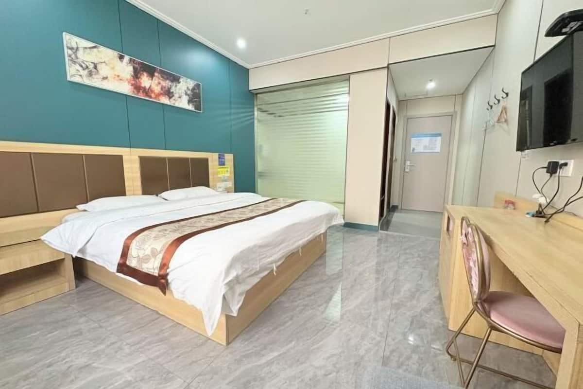 A hotel room with a bed, a desk, and a TV.
