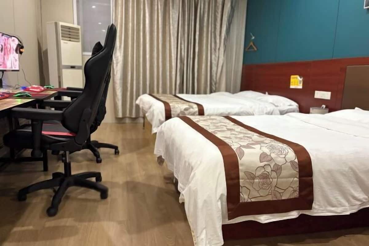 A hotel room with two beds, a desk with a computer, and a chair.