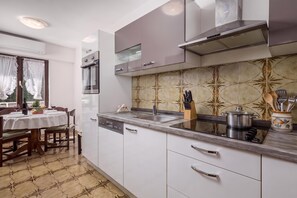 A modern kitchen with white cabinets, a stainless steel range hood, and a tiled backsplash. - House Rose With Private Pool And Garden, Pinezići, Croatia (Pinezići)