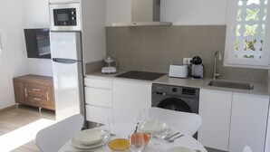 A modern kitchen with a built-in oven, microwave, and dishwasher. There is a dining table set with plates, glasses, and cutlery.
