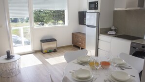 A modern kitchen with a dining table set for four, a refrigerator, microwave, and a small oven.
