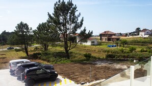 Un espace de stationnement avec plusieurs voitures, un champ d’herbe et des maisons en arrière-plan.