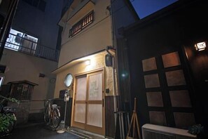Un edificio con puerta y ventanas de madera, una bicicleta y un pequeño espacio al aire libre.