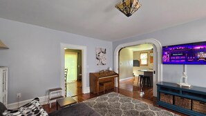 A living room with a sofa, a coffee table, and a TV mounted on the wall. - Charming 3-bedroom farmhouse 1 hour from Beaver Stadium (Williamsport)