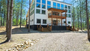 A modern multi-story building with a wooden deck and a staircase leading to a balcony.