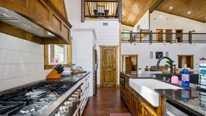 A spacious kitchen with a large gas stove, wooden cabinets, and a two-level balcony.