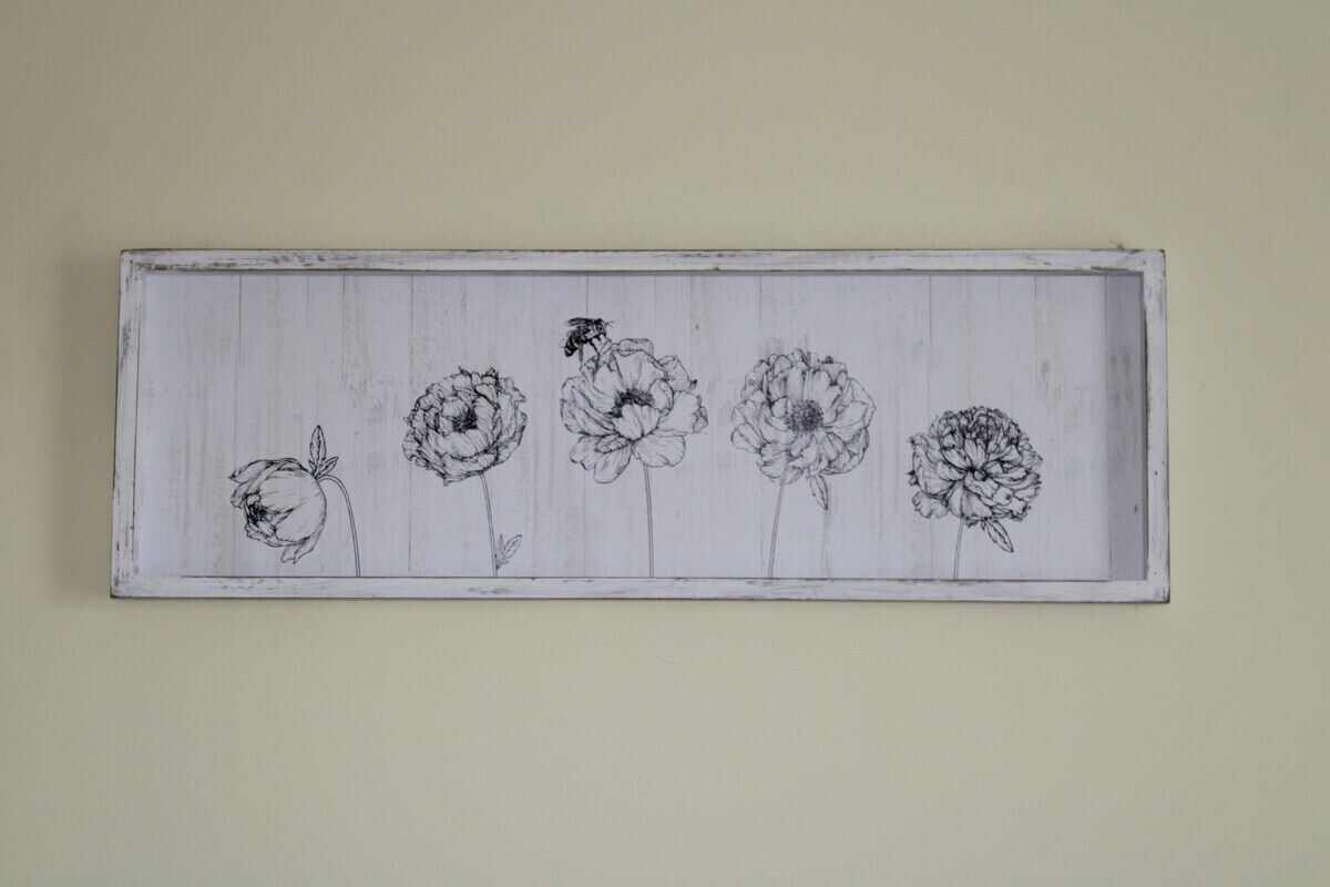 En rektangulär träpanel med fem svartvita skisser av blommor och ett bi.