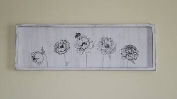 En rektangulär träpanel med fem svartvita skisser av blommor och ett bi.