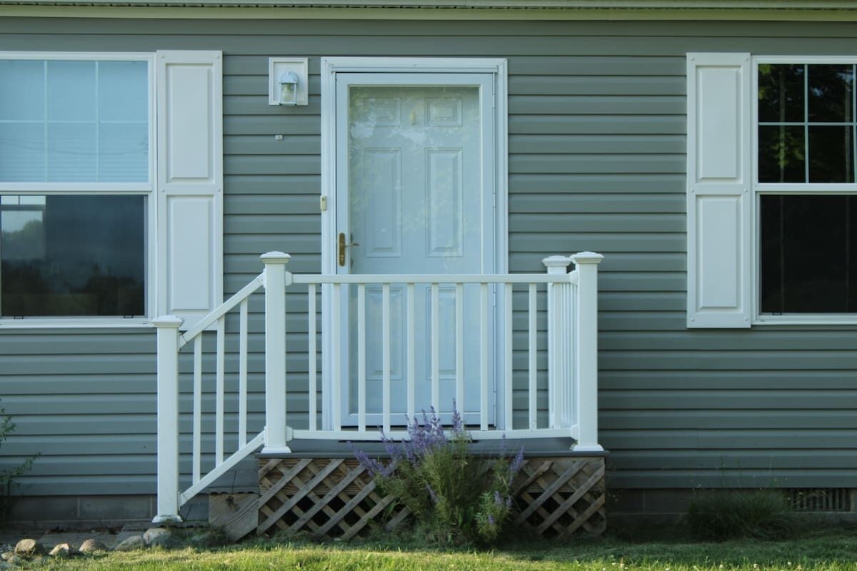 A house with a front porch, a white door, and a window with shutters.