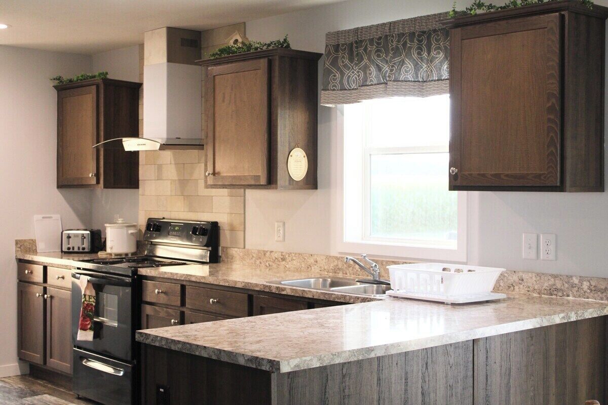 A modern kitchen with dark wood cabinets, a stainless steel stove, a built-in oven, and a large island with a sink.