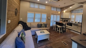 A modern living room with a sofa, a coffee table, and a kitchen area with a counter and stools. - Luxurious quiet cottage on 25 acre rescue farm. In the forest above Port Angeles (Port Angeles)
