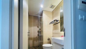 A bathroom with a glass shower enclosure, a white toilet, and a sink with a mirror.