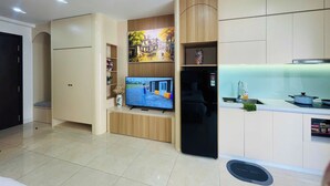 A modern kitchen with a built-in refrigerator, a flat-screen TV, and a dining area with a sink and countertop.