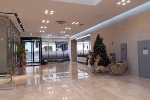 A lobby with a Christmas tree, seating area, and a glass door entrance.