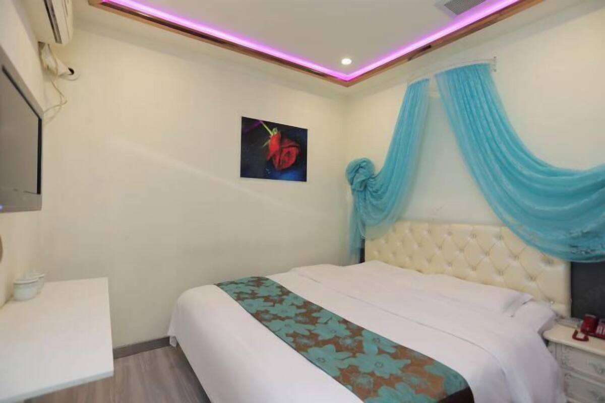 Une chambre à coucher comprenant un lit, une table de chevet, un climatiseur fixé au mur et un tableau.