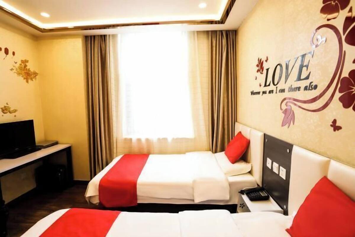 Une chambre d’hôtel avec deux lits, une télévision, un bureau et un mur décoré sur le thème de l’amour.
