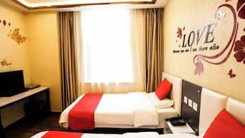 A hotel room with two beds, a TV, a desk, and a wall with a LOVE-themed decoration.