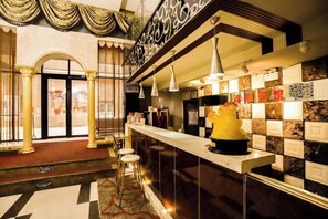 Una zona de bar con mostrador de mármol, lámparas colgantes y un elemento decorativo central.