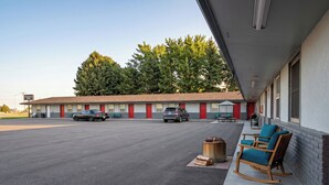 A motel with a parking lot, two cars parked, and a row of blue rocking chairs outside. - KJ's Inn and Suites By OYO Gettysburg U.S. Hwy 212 (Gettysburg)