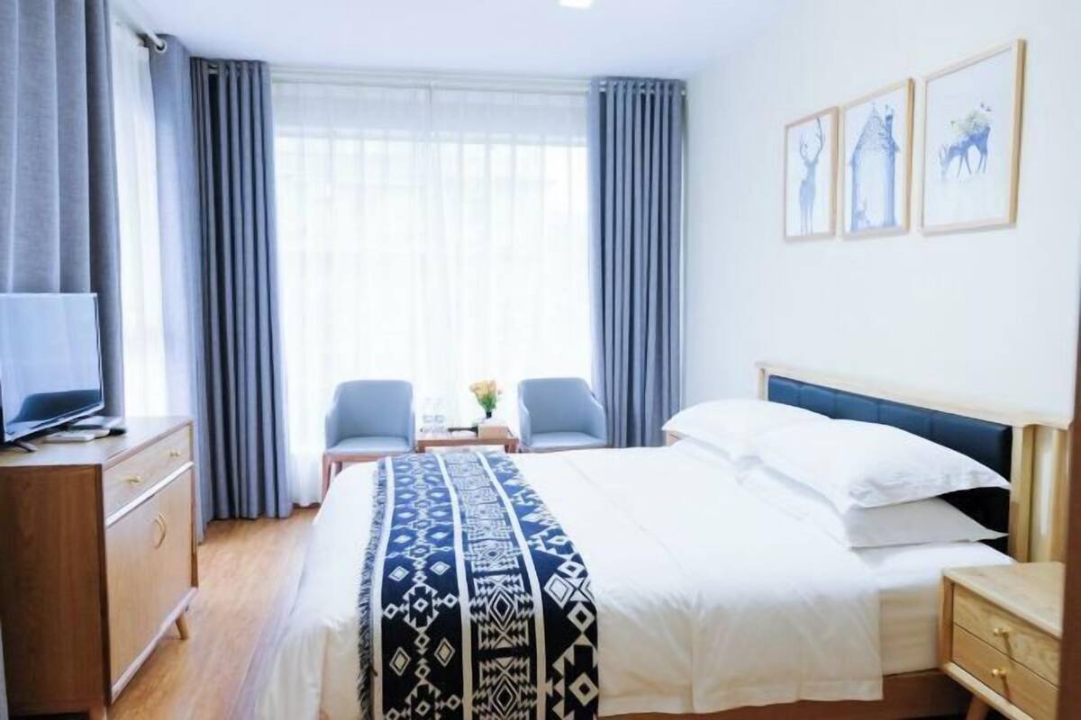 A hotel room with a bed, a TV, a desk, and a chair.
