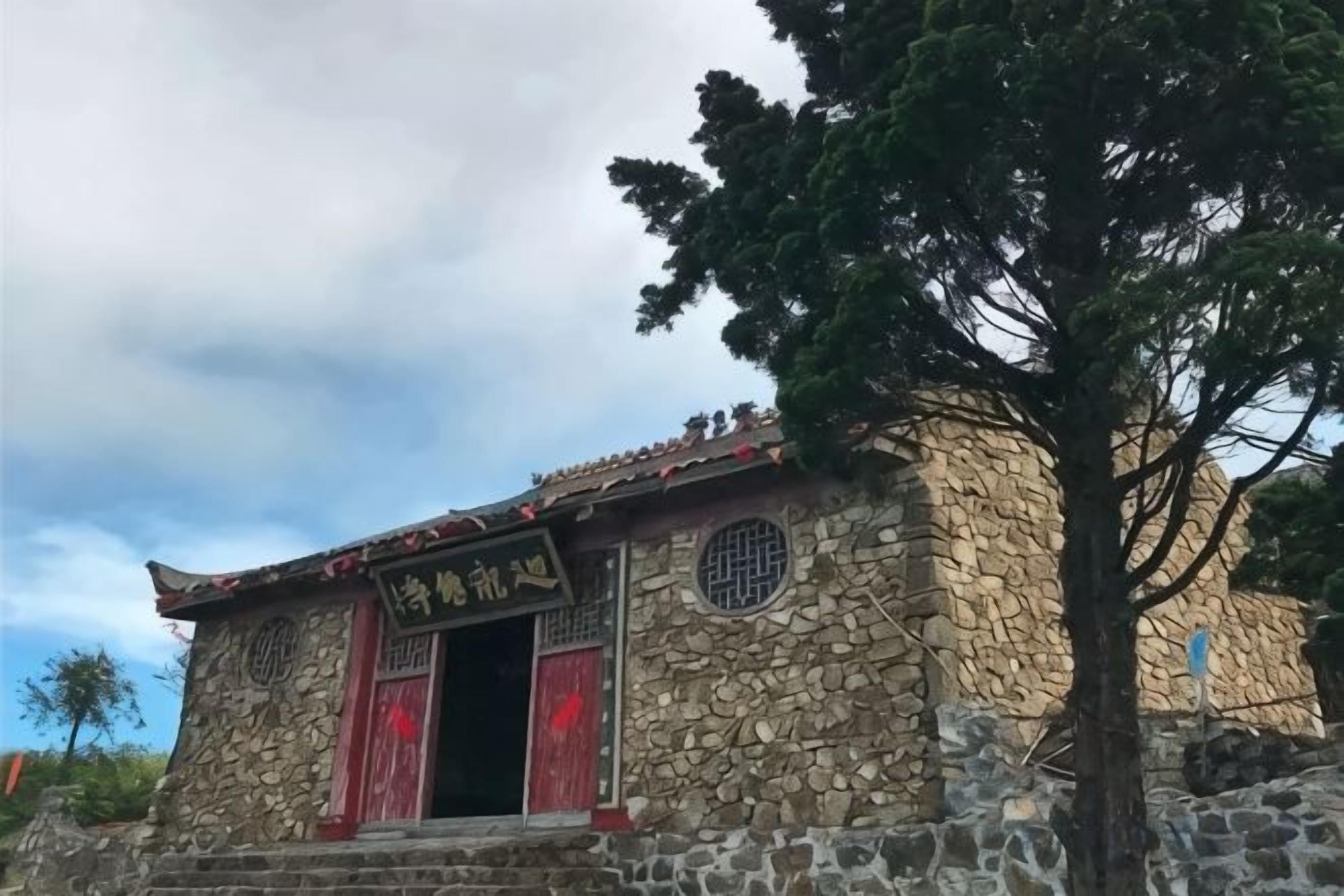 A stone building with a traditional design, featuring a doorway and a window with a decorative grille.