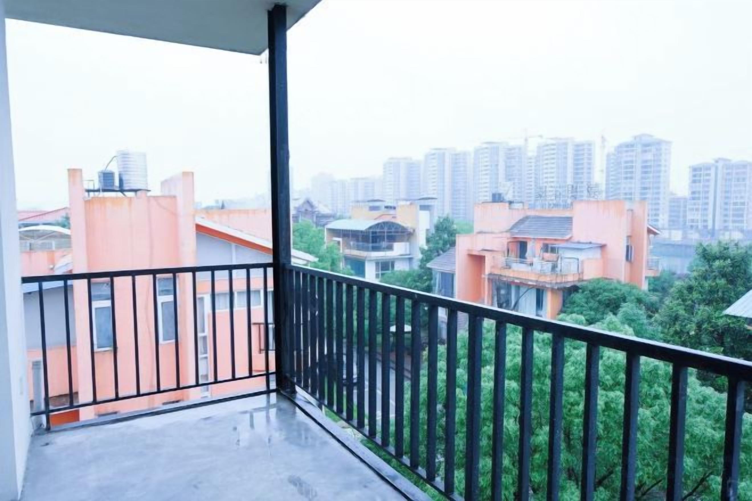 A balcony with a view of surrounding buildings and greenery.