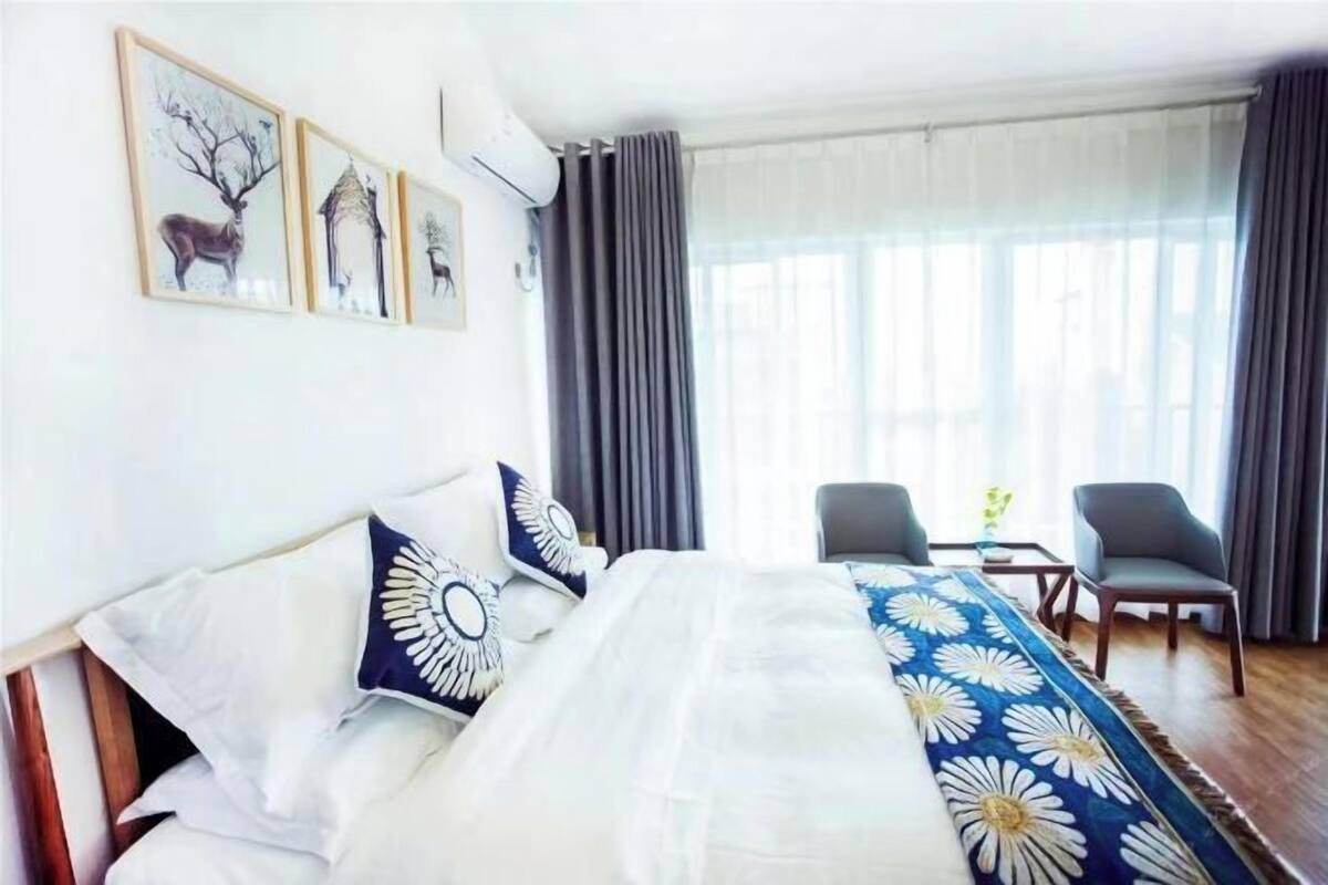 A hotel room with a bed, a desk, two chairs, and a window with curtains.