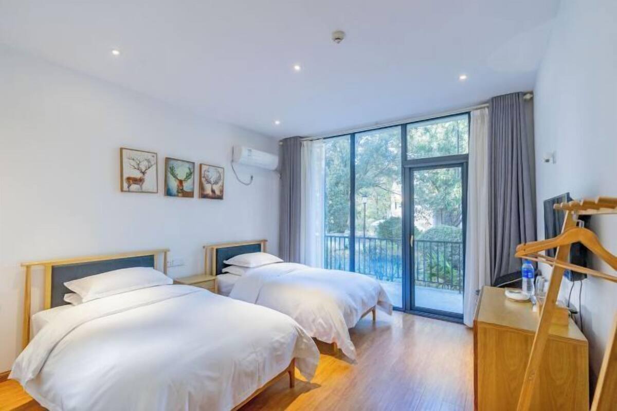 A hotel room with two beds, a balcony, and artwork on the wall.