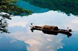 Una masa de agua tranquila con una lancha que transporta a una persona y un objeto cilíndrico.