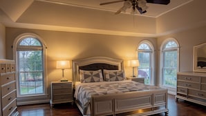 A bedroom with a large bed, two bedside tables, a ceiling fan, and arched windows. - Spacious 5-bedroom farmhouse in peaceful Nokesville with Pool (Nokesville)