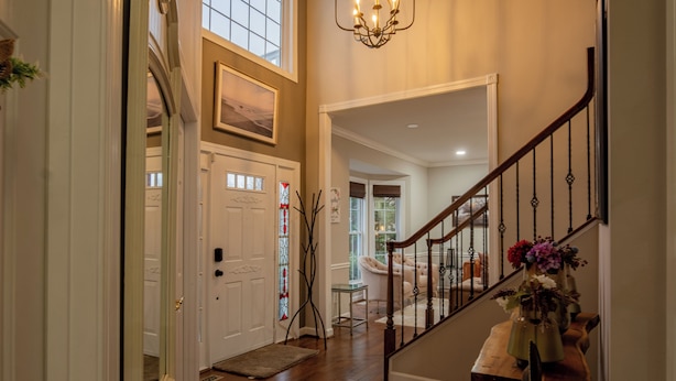 A staircase with a wooden handrail and a black metal railing, leading to a room with a white door and a stained glass window. - Spacious 5-bedroom farmhouse in peaceful Nokesville with Pool (Nokesville)