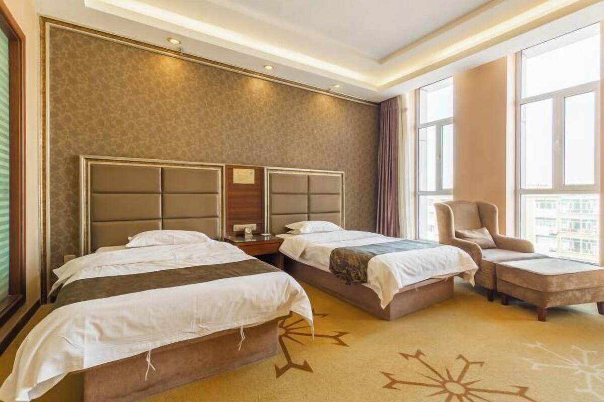 A hotel room with two beds, a sofa, and a chair.