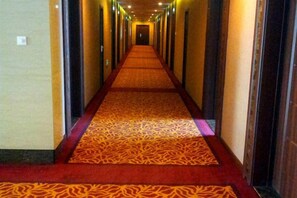 A hotel hallway with carpeted floors and doors on both sides. - Royal Hotel (Tuquan)