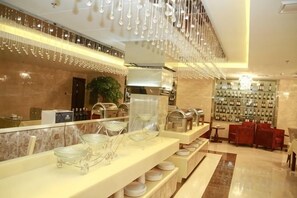 A hotel lobby with a reception desk, seating area, and a wall of amenities. - Royal Hotel (Tuquan)