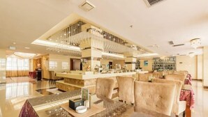 A spacious lobby with a high ceiling, a central bar area, and plush seating. - Royal Hotel (Tuquan)