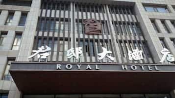 A hotel with a modern facade, featuring a prominent sign with the name 'ROYAL HOTEL' in English and Chinese characters.