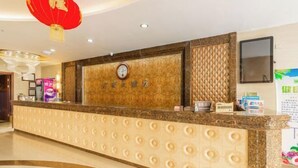 A hotel reception area with a marble counter, a clock, and a red lantern. - Royal Hotel (Tuquan)