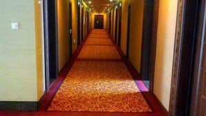 A long, narrow hallway with a patterned carpet and doors on both sides. - Royal Hotel (Tuquan)