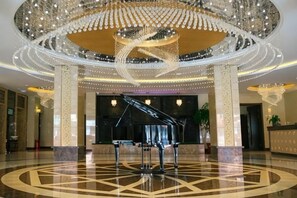 A grand lobby with a grand piano, a large chandelier, and a circular floor design. - Royal Hotel (Tuquan)