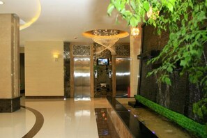 A hotel lobby with a reception desk, a reception area, and a large plant. - Royal Hotel (Tuquan)