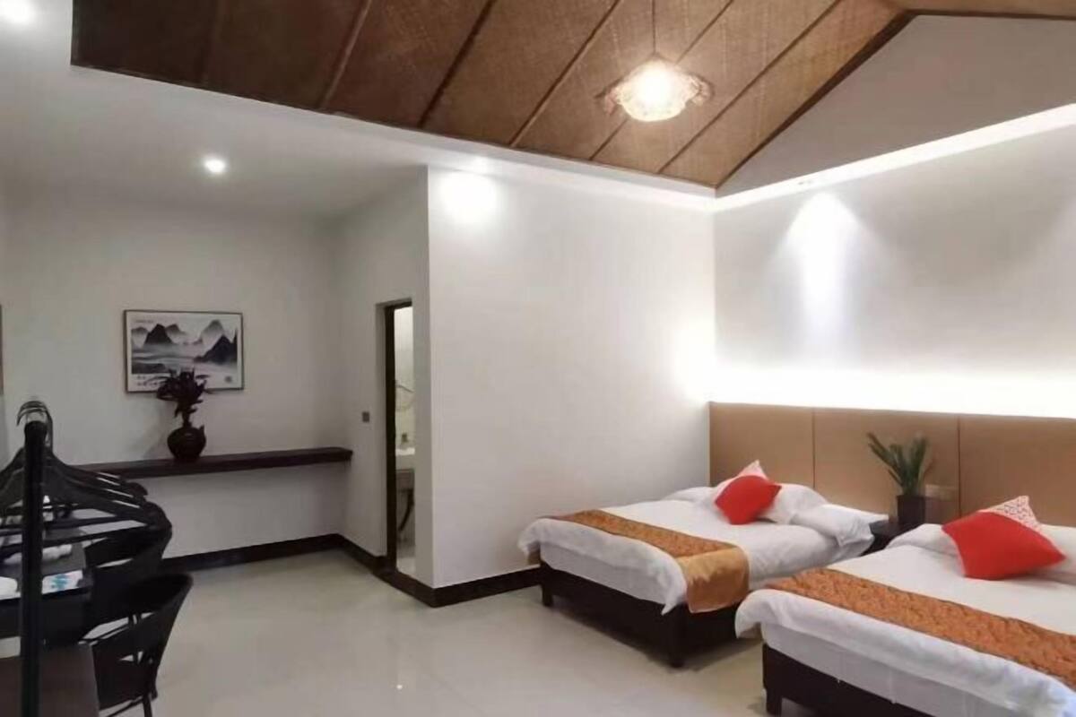 Een hotelkamer met twee bedden, een eettafel en een plafondlamp.