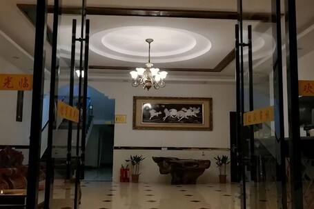A lobby with a chandelier, a framed artwork, a reception desk, and a staircase.. Longhushan Fengshanxige Homestay