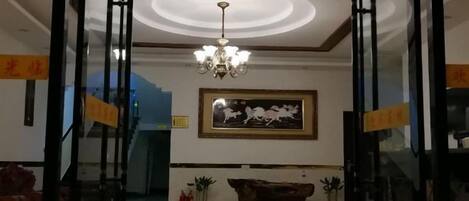 A lobby with a chandelier, a framed artwork, and a staircase.