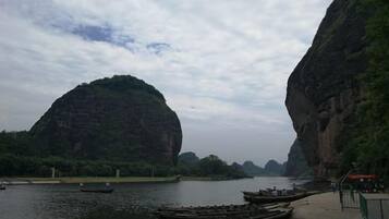 A river with boats, a dock, and a large rock formation.
