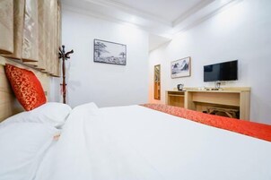 Una habitación de hotel con cama, televisor, escritorio y obras de arte en las paredes.