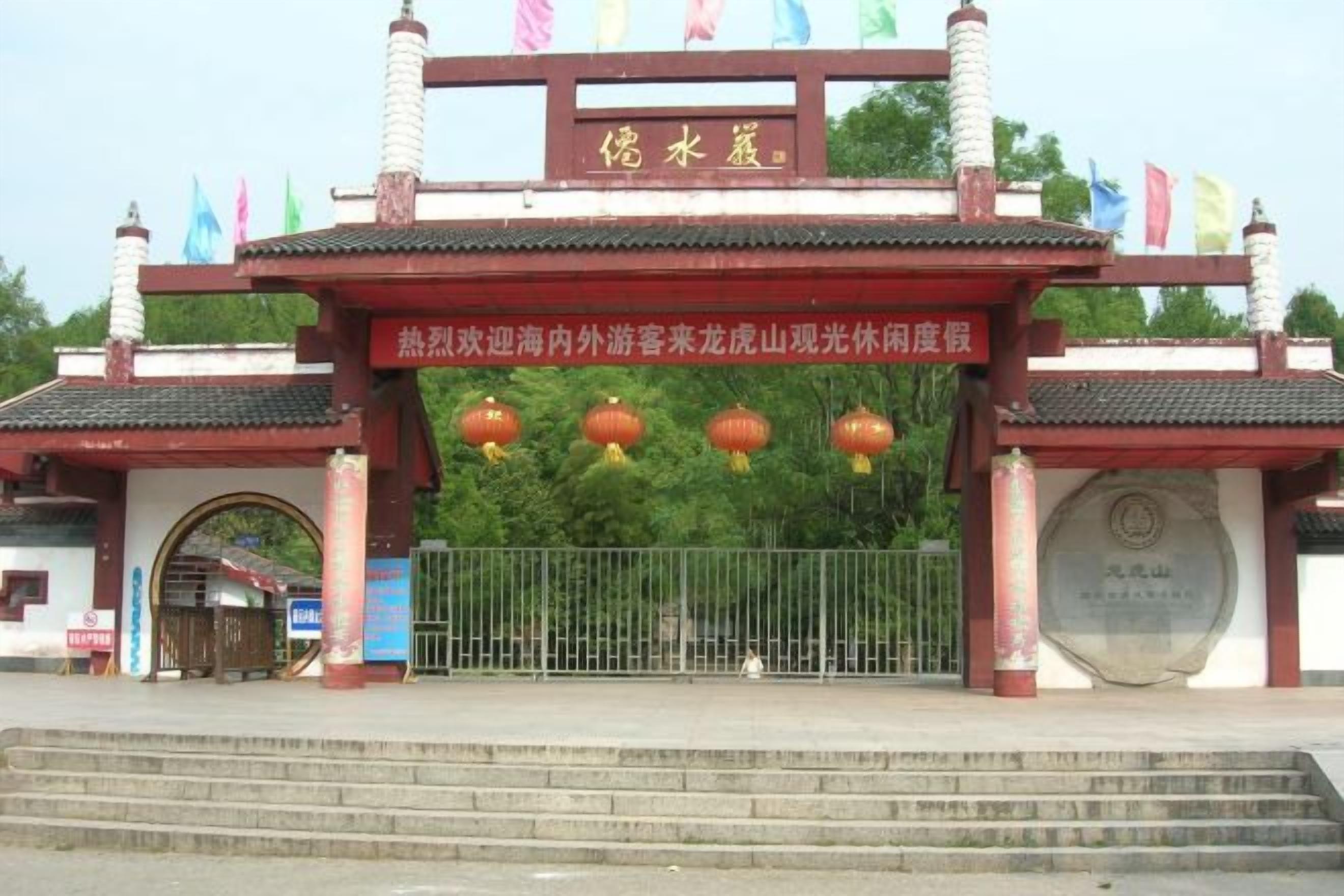 A traditional Chinese gate with a plaque, a tiled roof, and a metal gate.